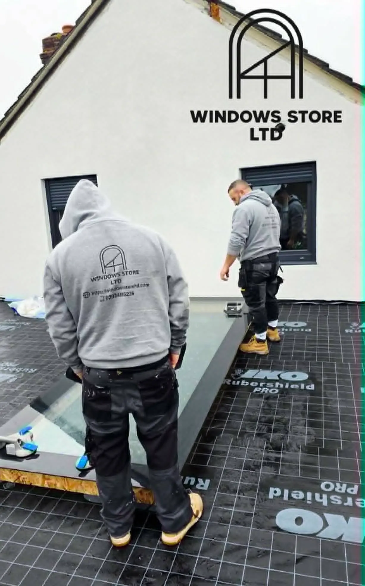 Two Windows Store Ltd fitters installing a flat rooflight on an extension roof, house gable behind, London